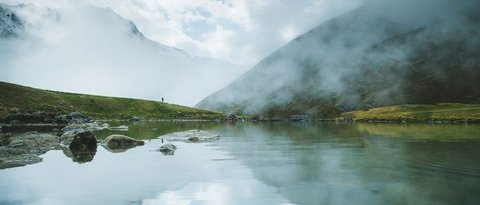 Bilder aus der Sportalm Bergsee mit Reflexion und Nebel an einem bewölkten Tag