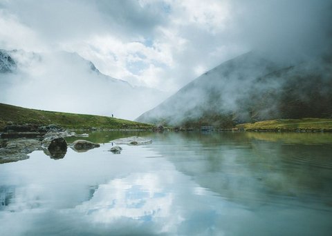 Bilder aus der Sportalm Bergsee mit Reflexion und Nebel an einem bewölkten Tag