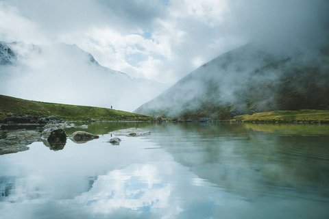 Bilder aus der Sportalm Bergsee mit Reflexion und Nebel an einem bewölkten Tag