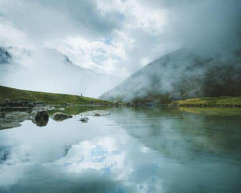 Bilder aus der Sportalm Bergsee mit Reflexion und Nebel an einem bewölkten Tag