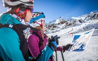 Zwei Skifahrer lesen eine Skipistenkarte vor einem schneebedeckten Berg