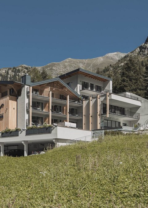 Bilder aus der Sportalm Modernes Hotel in den Bergen mit grüner Wiese und klarem Himmel