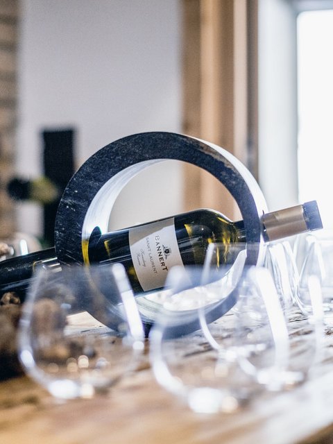 Bilder aus der Sportalm Weinflasche in einem runden Halter auf einem Tisch mit mehreren Weingläsern