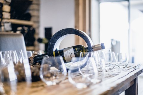 Bilder aus der Sportalm Weinflasche in einem runden Halter auf einem Tisch mit mehreren Weingläsern