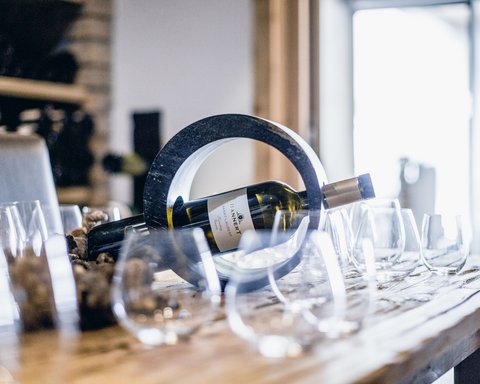 Bilder aus der Sportalm Weinflasche in einem runden Halter auf einem Tisch mit mehreren Weingläsern