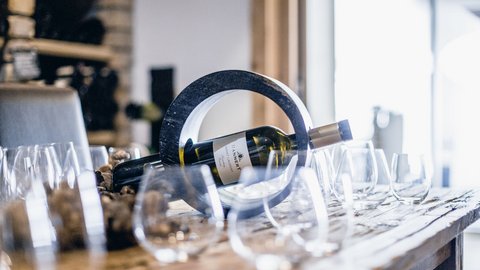 Bilder aus der Sportalm Weinflasche in einem runden Halter auf einem Tisch mit mehreren Weingläsern