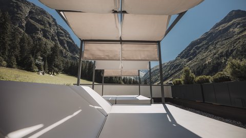 Bilder aus der Sportalm Liegestühle mit Sonnenschutz auf Terrasse vor Berglandschaft bei klarem Himmel