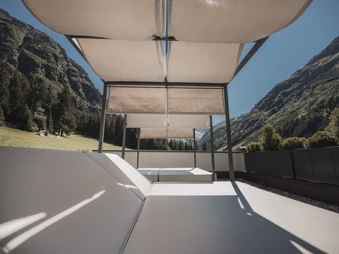 Bilder aus der Sportalm Liegestühle mit Sonnenschutz auf Terrasse vor Berglandschaft bei klarem Himmel