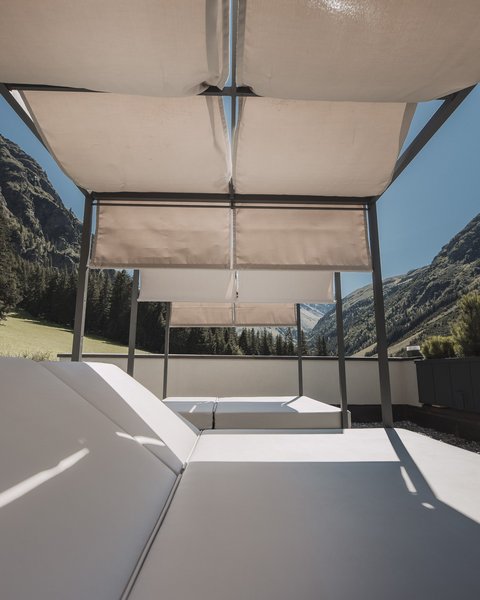 Bilder aus der Sportalm Liegestühle mit Sonnenschutz auf Terrasse vor Berglandschaft bei klarem Himmel