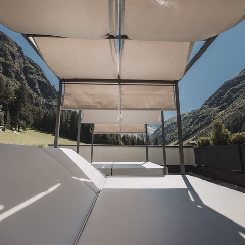 Bilder aus der Sportalm Liegestühle mit Sonnenschutz auf Terrasse vor Berglandschaft bei klarem Himmel