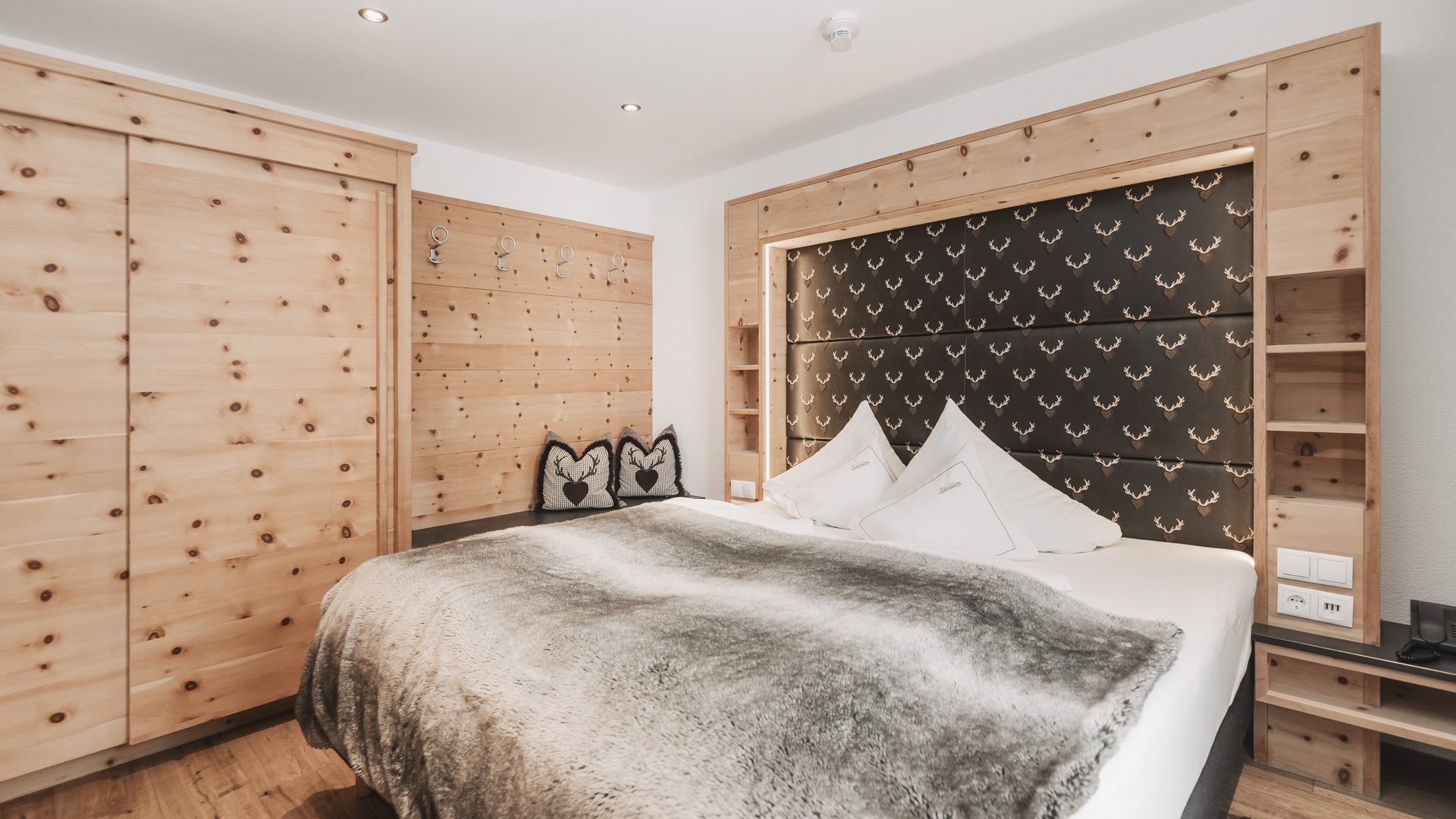 Everything about your Sportalm holiday Cozy bedroom with wooden furniture and deer pattern on the headboard