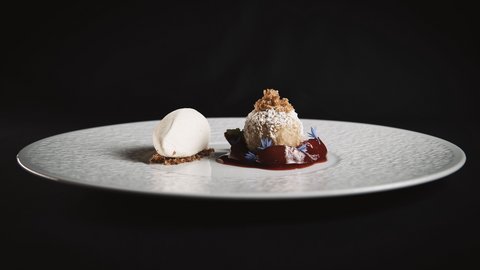 Bilder aus der Sportalm Feines Dessert mit hellem Eis und Kugel mit Puderzucker und roter Sauce