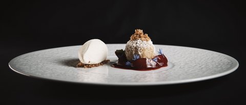Bilder aus der Sportalm Feines Dessert mit hellem Eis und Kugel mit Puderzucker und roter Sauce