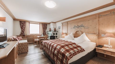 Pictures from Sportalm Bright hotel room with rustic wooden furniture and plaid bedspread