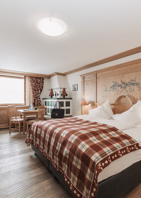 Pictures from Sportalm Bright hotel room with rustic wooden furniture and plaid bedspread