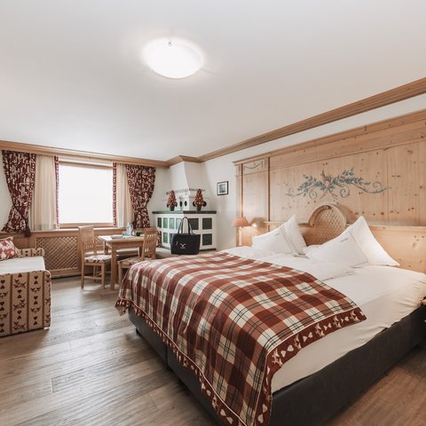 Bilder aus der Sportalm Helles Hotelzimmer mit rustikalem Holzmobiliar und kariertem Bettüberwurf