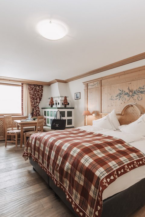 Bilder aus der Sportalm Helles Hotelzimmer mit rustikalem Holzmobiliar und kariertem Bettüberwurf