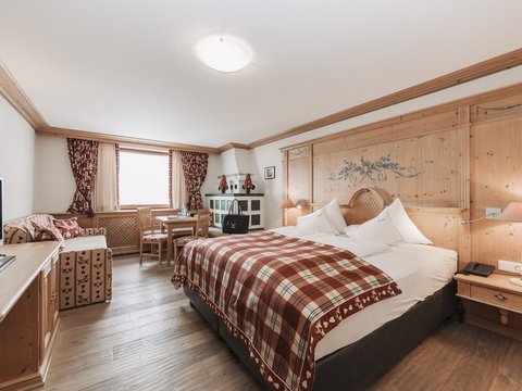 Bilder aus der Sportalm Helles Hotelzimmer mit rustikalem Holzmobiliar und kariertem Bettüberwurf