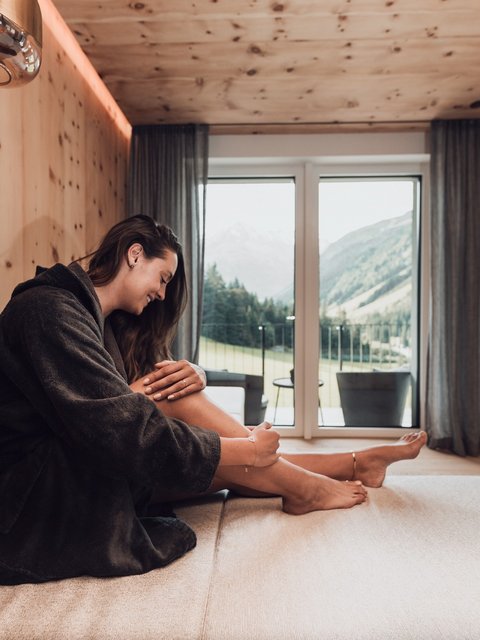 Bilder aus der Sportalm Frau im Bademantel entspannt sich in modernem Zimmer mit Bergblick