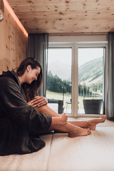 Bilder aus der Sportalm Frau im Bademantel entspannt sich in modernem Zimmer mit Bergblick