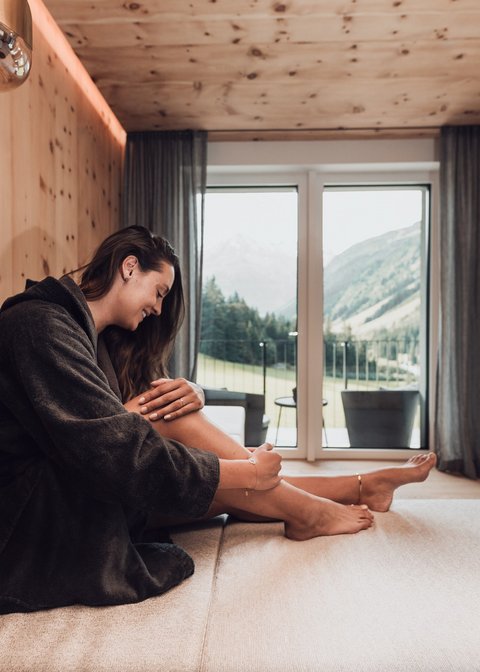 Bilder aus der Sportalm Frau im Bademantel entspannt sich in modernem Zimmer mit Bergblick