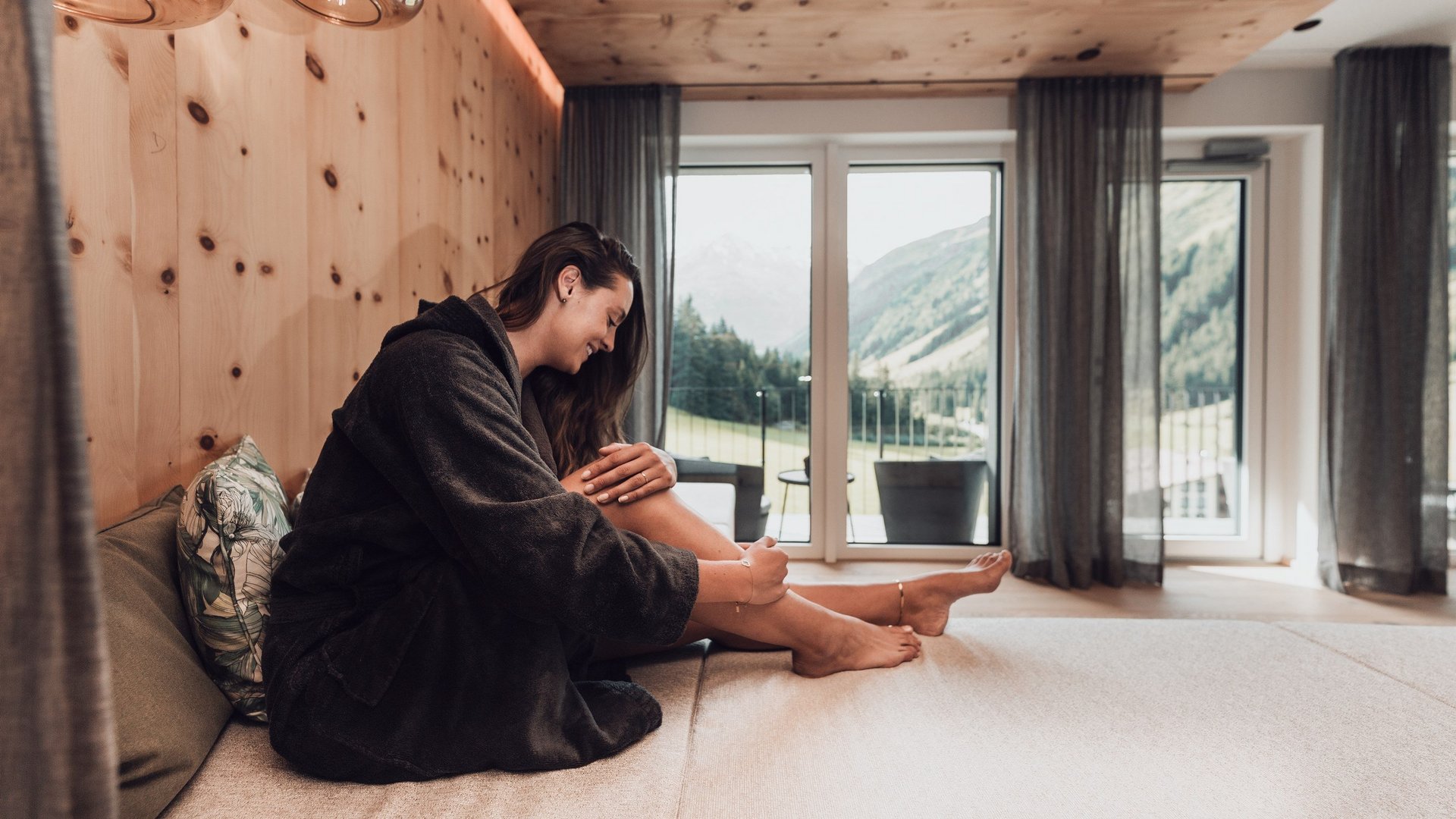 Wellness hotel in Pitztal: pure relaxation Woman in bathrobe relaxing in modern room with mountain view