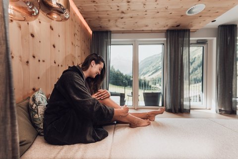 Bilder aus der Sportalm Frau im Bademantel entspannt sich in modernem Zimmer mit Bergblick