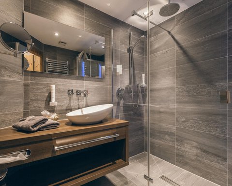 Pictures from Sportalm Modern bathroom with gray tiles, wooden vanity, and glass shower enclosure