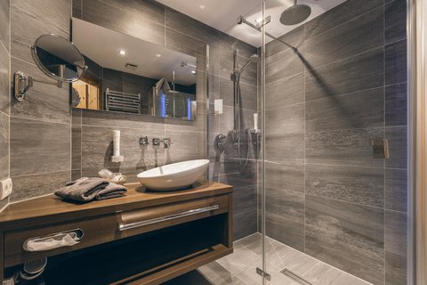 Pictures from Sportalm Modern bathroom with gray tiles, wooden vanity, and glass shower enclosure