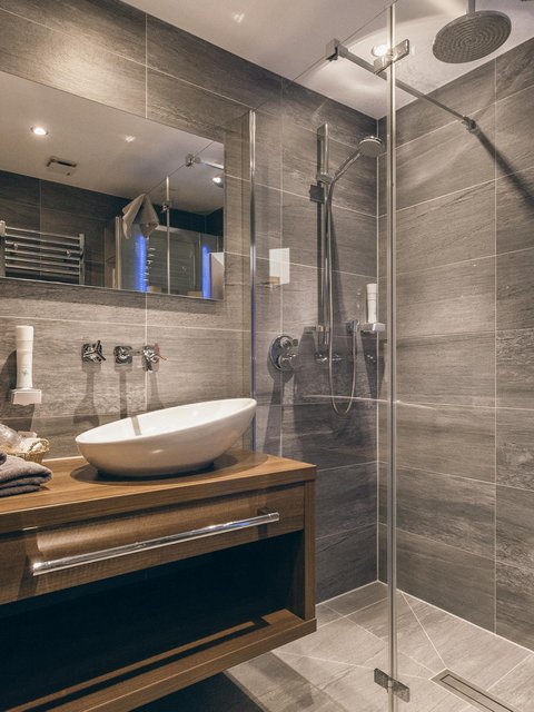 Pictures from Sportalm Modern bathroom with gray tiles, wooden vanity, and glass shower enclosure