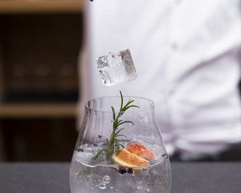 Bilder aus der Sportalm Eiswürfel wird mit einer Zange in ein mit Kräutern und Früchten dekoriertes Getränk gelegt