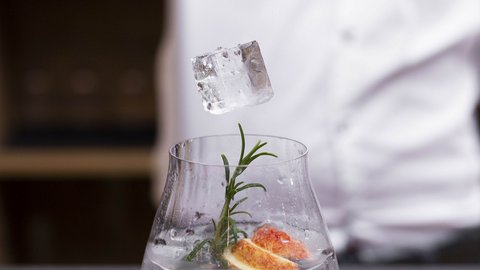 Bilder aus der Sportalm Eiswürfel wird mit einer Zange in ein mit Kräutern und Früchten dekoriertes Getränk gelegt