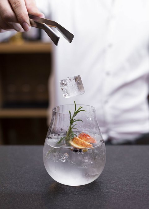 Pictures from Sportalm Ice cube dropped with tongs into a glass garnished with herbs and fruit