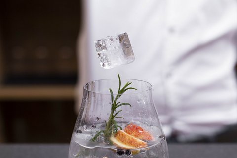 Pictures from Sportalm Ice cube dropped with tongs into a glass garnished with herbs and fruit