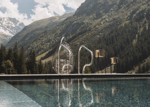 Bilder aus der Sportalm Pool vor Berglandschaft mit Sonnenschein und Wolken