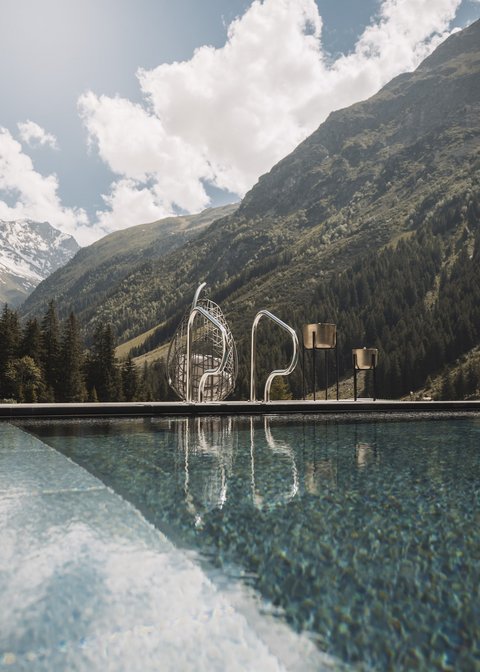 Bilder aus der Sportalm Pool vor Berglandschaft mit Sonnenschein und Wolken