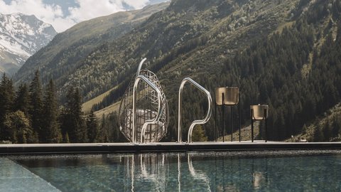 Bilder aus der Sportalm Pool vor Berglandschaft mit Sonnenschein und Wolken