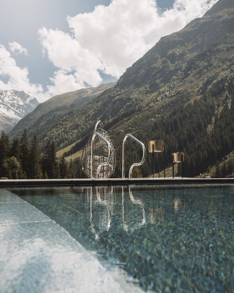 Bilder aus der Sportalm Pool vor Berglandschaft mit Sonnenschein und Wolken