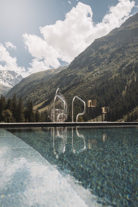 Bilder aus der Sportalm Pool vor Berglandschaft mit Sonnenschein und Wolken