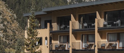 Bilder aus der Sportalm Hotel mit Balkonen vor bewaldetem Berghang und Schnee auf Gipfeln