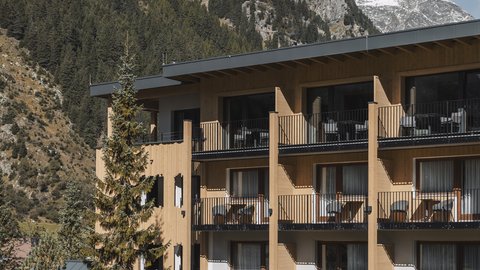 Bilder aus der Sportalm Hotel mit Balkonen vor bewaldetem Berghang und Schnee auf Gipfeln