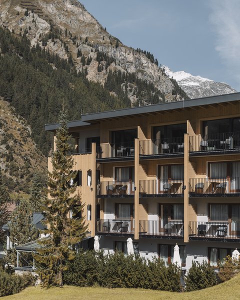 Bilder aus der Sportalm Hotel mit Balkonen vor bewaldetem Berghang und Schnee auf Gipfeln