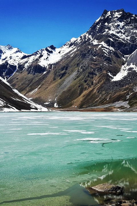 Bilder aus der Sportalm Gefrorener Bergsee mit schneebedeckten Gipfeln unter klarem blauem Himmel