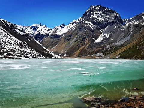 Bilder aus der Sportalm Gefrorener Bergsee mit schneebedeckten Gipfeln unter klarem blauem Himmel