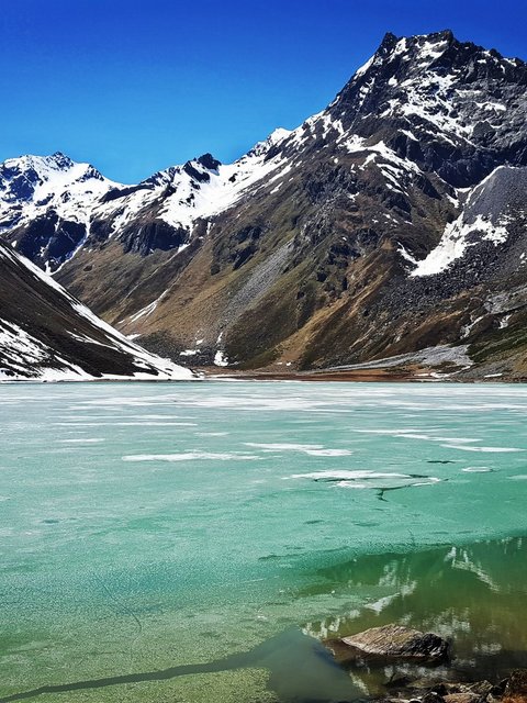 Bilder aus der Sportalm Gefrorener Bergsee mit schneebedeckten Gipfeln unter klarem blauem Himmel