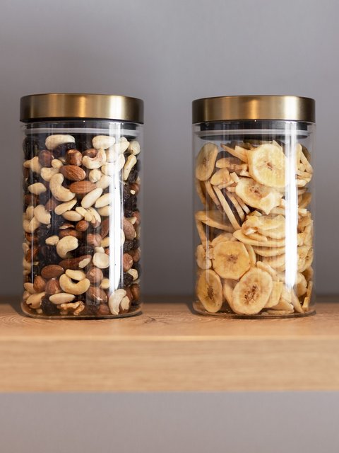 Bilder aus der Sportalm Vier Gläser mit Nüssen und Bananenchips auf einem Holzregal