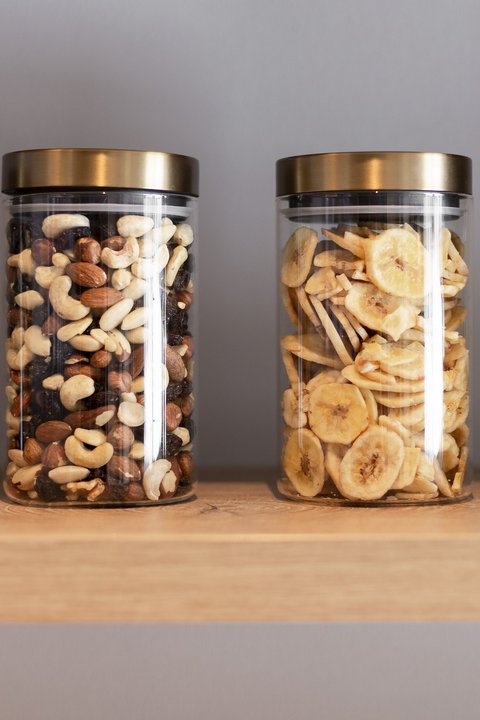 Bilder aus der Sportalm Vier Gläser mit Nüssen und Bananenchips auf einem Holzregal