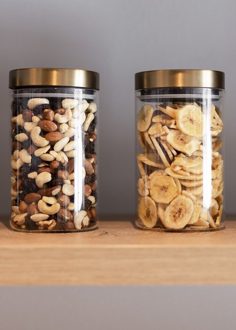 Bilder aus der Sportalm Vier Gläser mit Nüssen und Bananenchips auf einem Holzregal