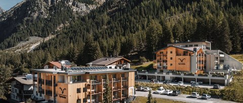 Bilder aus der Sportalm Hotelgebäude umgeben von Bergen und Wäldern an einem sonnigen Tag