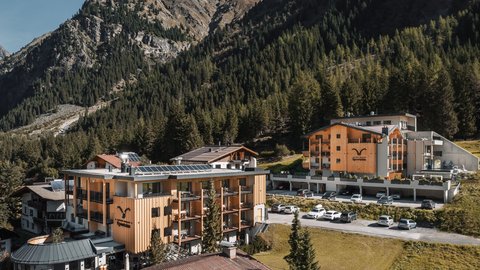 Bilder aus der Sportalm Hotelgebäude umgeben von Bergen und Wäldern an einem sonnigen Tag